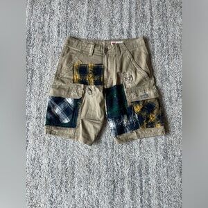 Tan cargo jorts with distressed flannel patches.